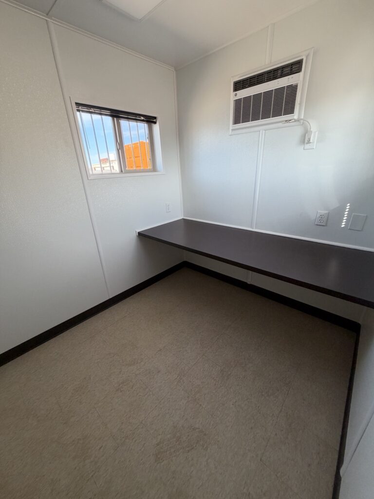 Inside a 40 foot container all office with countertop desk, air conditioning, and window
